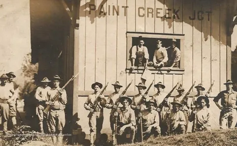Armed minors lining up for a group shot at paint creek during the first miners rebellion
