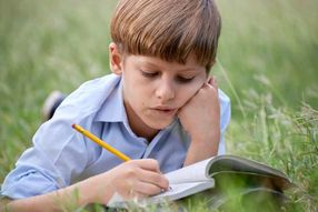 A child writing outdoors on a sunny day.